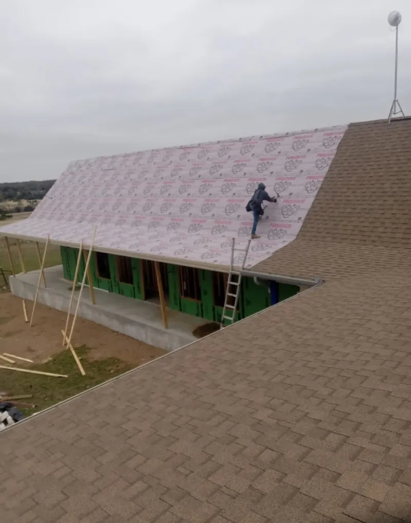 Worker preparing underlayment for a metal roof installation in New Castle